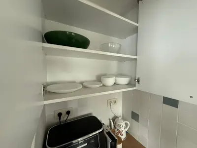 a kitchen with shelves with bowls and a microwave at Smile Old City Apartment with Free parking and Sea view in Varna City