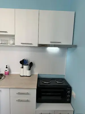 a kitchen with a black stove and white cabinets at Nana Studio Sunny Beach in Sunny Beach