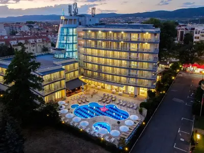 a hotel building with a pool and tables and umbrellas at Nana Studio Sunny Beach in Sunny Beach