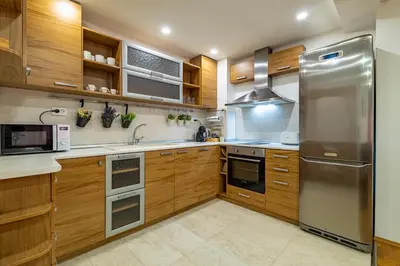 a kitchen with wooden cabinets and a stainless steel refrigerator at Sunny apartment in the center of Varna for 5Guests in Varna City