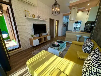a living room with a yellow couch and a tv at Sea View Apartments Residence Лазурен бряг in Burgas City