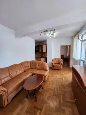 a living room with a brown leather couch and a table at Лукс Апартамент Лазур с безплатен паркинг in Pomorie