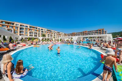 a group of people sitting around a swimming pool at Premier Fort Beach Apartment with Pool & Sea View in Sveti Vlas