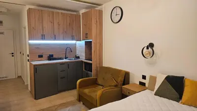 a living room with a couch and a clock on the wall at Vladan apartments in Sozopol