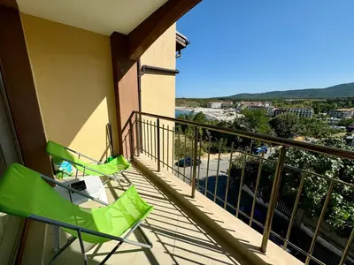 a balcony with two green chairs and a view at Елскер in Tsarevo