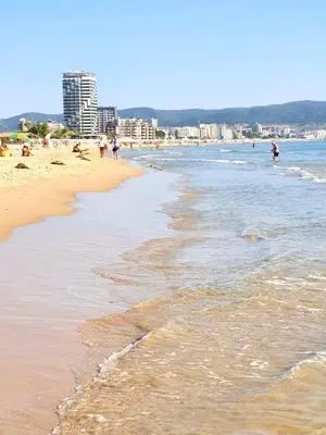 a beach with people in the water and buildings at Cacao in Sunny Beach