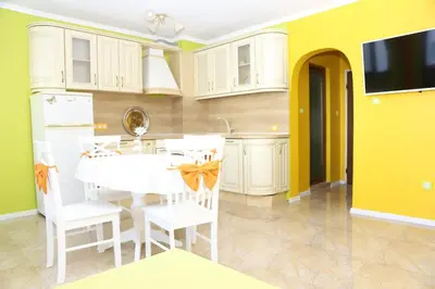 a kitchen with a white table and a yellow wall at Flora Deluxe Studio in Burgas City