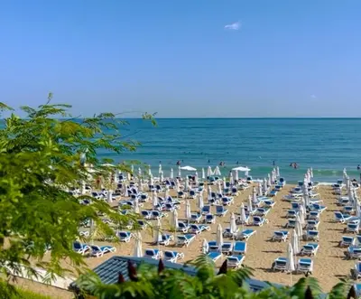 a beach with chairs and umbrellas and the ocean at Polarstar Apartment in Sveti Vlas