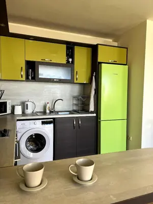 a kitchen with yellow cabinets and a green refrigerator at Морска Идилия in Burgas City