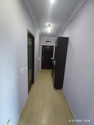a hallway with white walls and wooden floors and a black door at Central View Burgas in Burgas City