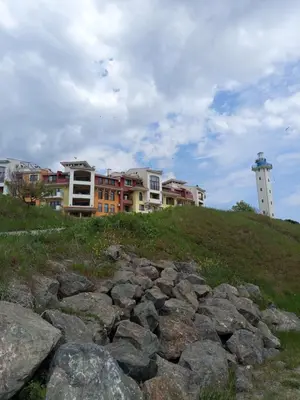a group of buildings on a hill with a lighthouse at Ваканционен Апартамент in Aheloy