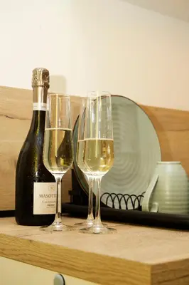 two glasses of white wine next to a bottle of wine at Tsaribrod Design Apartments in Varna City