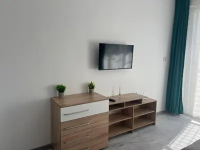 a wooden dresser with a tv on a wall at Sol e Mar Private Apartment in Sunny Beach