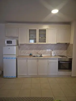 a kitchen with white cabinets and a sink and a refrigerator at Апартамент в отеле Premier Fort Beach in Sveti Vlas