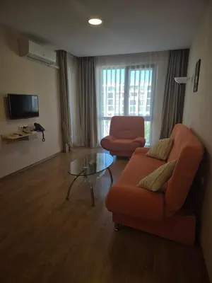 a living room with an orange couch and a glass table at Апартамент в отеле Premier Fort Beach in Sveti Vlas