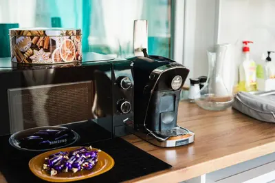 a microwave sitting on a counter with a plate of food at Апартамент Морски уют in Burgas City