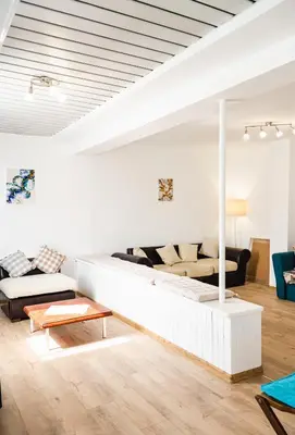 a white living room with a couch and a table at Апартамент Морски уют in Burgas City