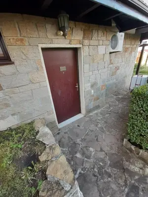 a brick house with a red door and a stone walkway at Dream apartment in sunny beach in Kosharitsa