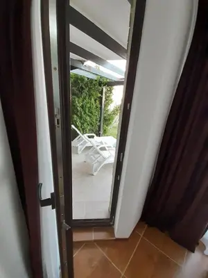 a glass door leading to a patio with a white chair at Dream apartment in sunny beach in Kosharitsa