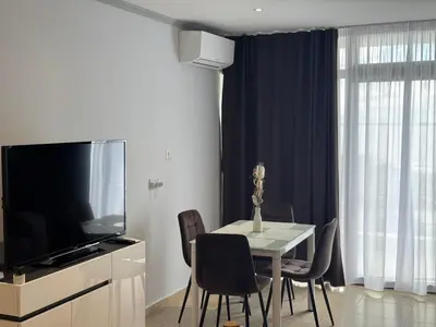 a dining room with a table with chairs and a television at Diamond by the Sea in Sveti Vlas