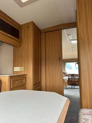 a room with a bed and wooden cabinets and a table at Каравана Кътче От Рая in Tsarevo