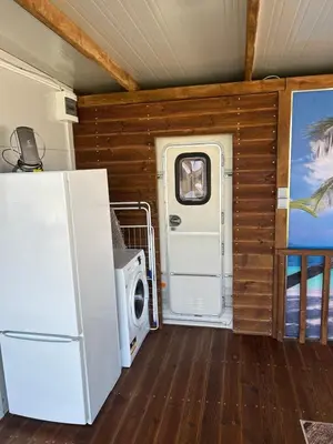 a kitchen with a refrigerator and a door in a room at Каравана Кътче От Рая in Tsarevo