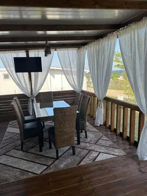 a dining room with a table and chairs on a balcony at Каравана Кътче От Рая in Tsarevo