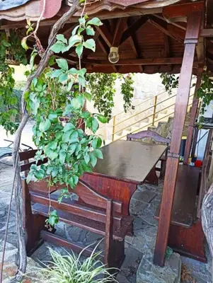 a wooden table and a bench under a roof at Paradise apartment Sozopol in Sozopol