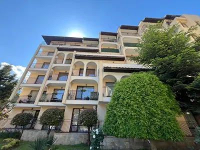 an apartment building with a tree in front of it at Rose Village Apartment in Sunny Beach