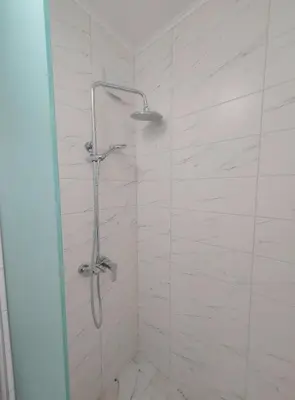 a shower in a bathroom with white tiles at Sofi's Harmony in Burgas City