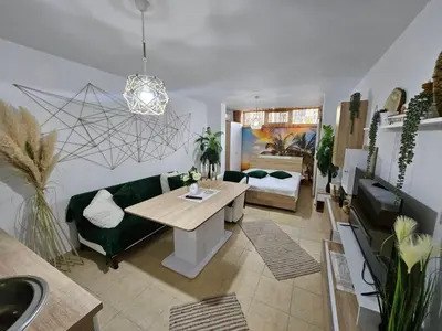 a living room with a table and a green couch at Tropical Chic for Two, Basement Studio Escape by Flat Mаnager in Ravda