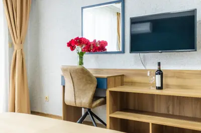 a room with a desk with a vase of red flowers at Hotel Laguna SPA in Sveti Vlas