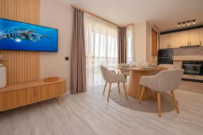 a living room with a dining table and a kitchen at Marina and Panorama Deluxe Apartments in Burgas City