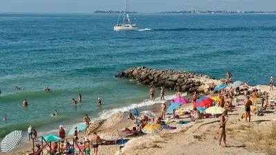 a group of people on a beach with a boat in the water at Marina and Panorama Deluxe Apartments in Burgas City