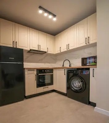 a kitchen with white cabinets and a washer and dryer at Marina and Panorama Deluxe Apartments in Burgas City