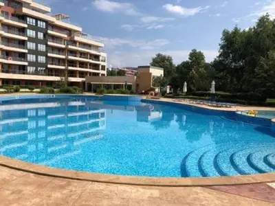 a large blue swimming pool in front of a building at Platinum apartment in Bŭnzareto