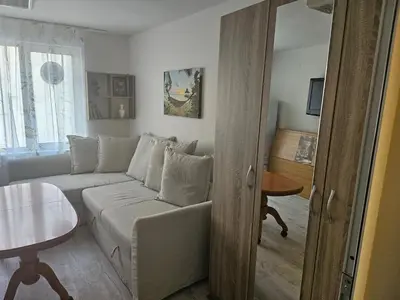 a living room with a white couch and a table at Малко студио в центъра на град Бургас II in Burgas City