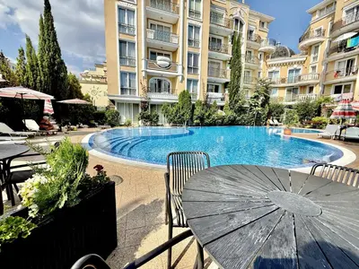 a large swimming pool with a table and an umbrella at Messembria Palace - Menada Apartments in Sunny Beach
