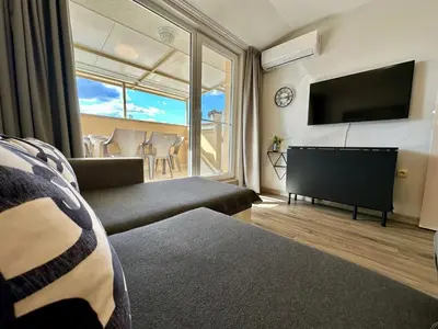 a living room with a couch and a flat screen tv at Messembria Palace - Menada Apartments in Sunny Beach