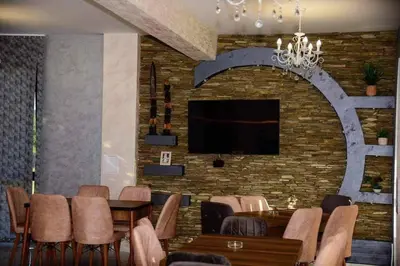 a dining room with a table and a tv on a brick wall at Къща за гости Силвия in Shkorpilovtsi