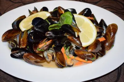 a plate of mussels and lemon slices on a table at Cosher Gardenia Palace Apt 6 Free Parking in Pomorie