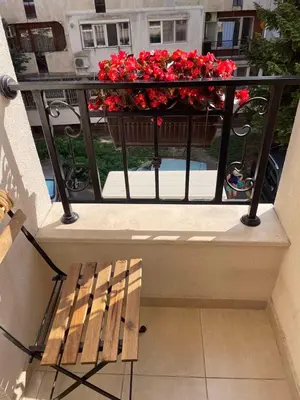 a balcony with a bench and a planter of red flowers at Deluxe studio beach Lazur in Burgas City
