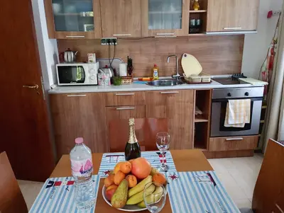 a kitchen with a plate of fruit and a bottle of wine at Етъра - 2 Rey&Mar Свети Влас in Sveti Vlas