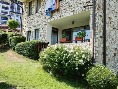 a stone house with bushes and flowers in front of it at Етъра - 2 Rey&Mar Свети Влас in Sveti Vlas