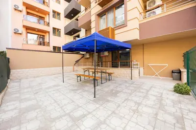a patio with blue umbrellas and benches in front of a building at Marea in Pomorie