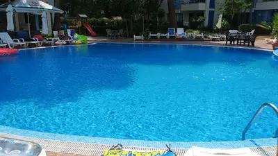 a large blue swimming pool with chairs and tables at Excelsior Prince ApartHotel in Sunny Beach