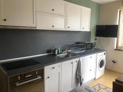 a kitchen with white cabinets and a sink and a dishwasher at Nesebar New Town Apartment in Nesebar
