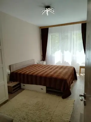 a bedroom with a bed with a brown comforter and a window at Comfort apartment near the beach in Varna City
