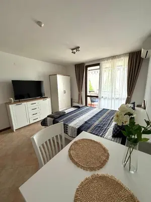 a bedroom with a bed and a table with a vase of flowers at Oasis Premium Studio in Lozenets