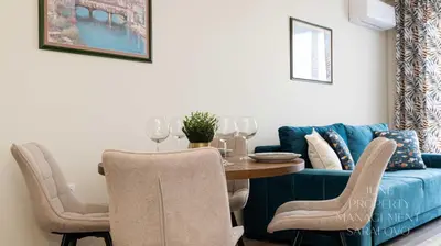 a dining room with a blue couch and a table at Sea-breeze retreat Zerini in Burgas City